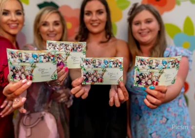 Invitées tenant des tirages photo personnalisés réalisés avec un photobooth lors d’un mariage